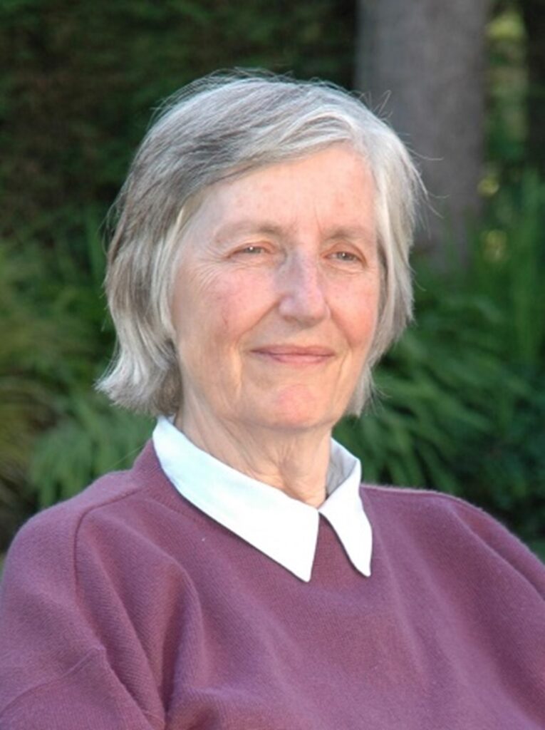 Photo of Sue smiling with trees behind her