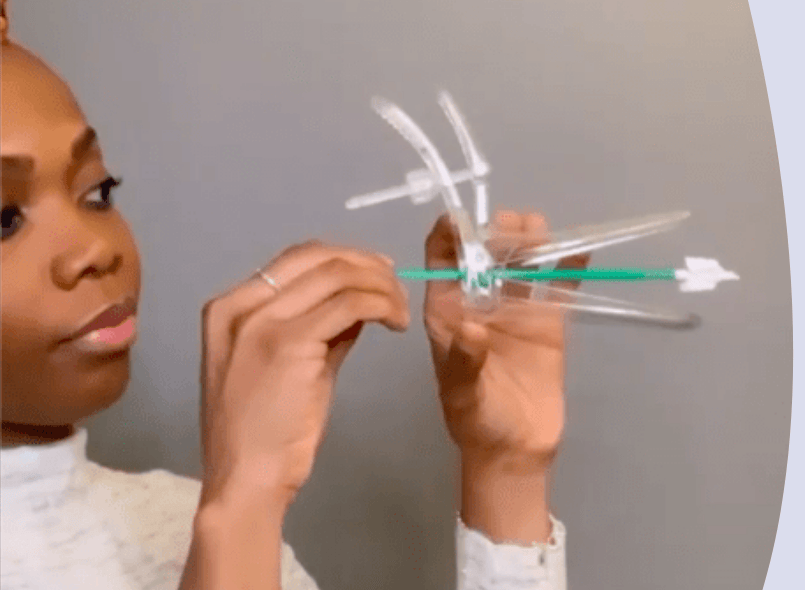 Dr Aziza Sesay is holding up a speculum and cervical screening brush