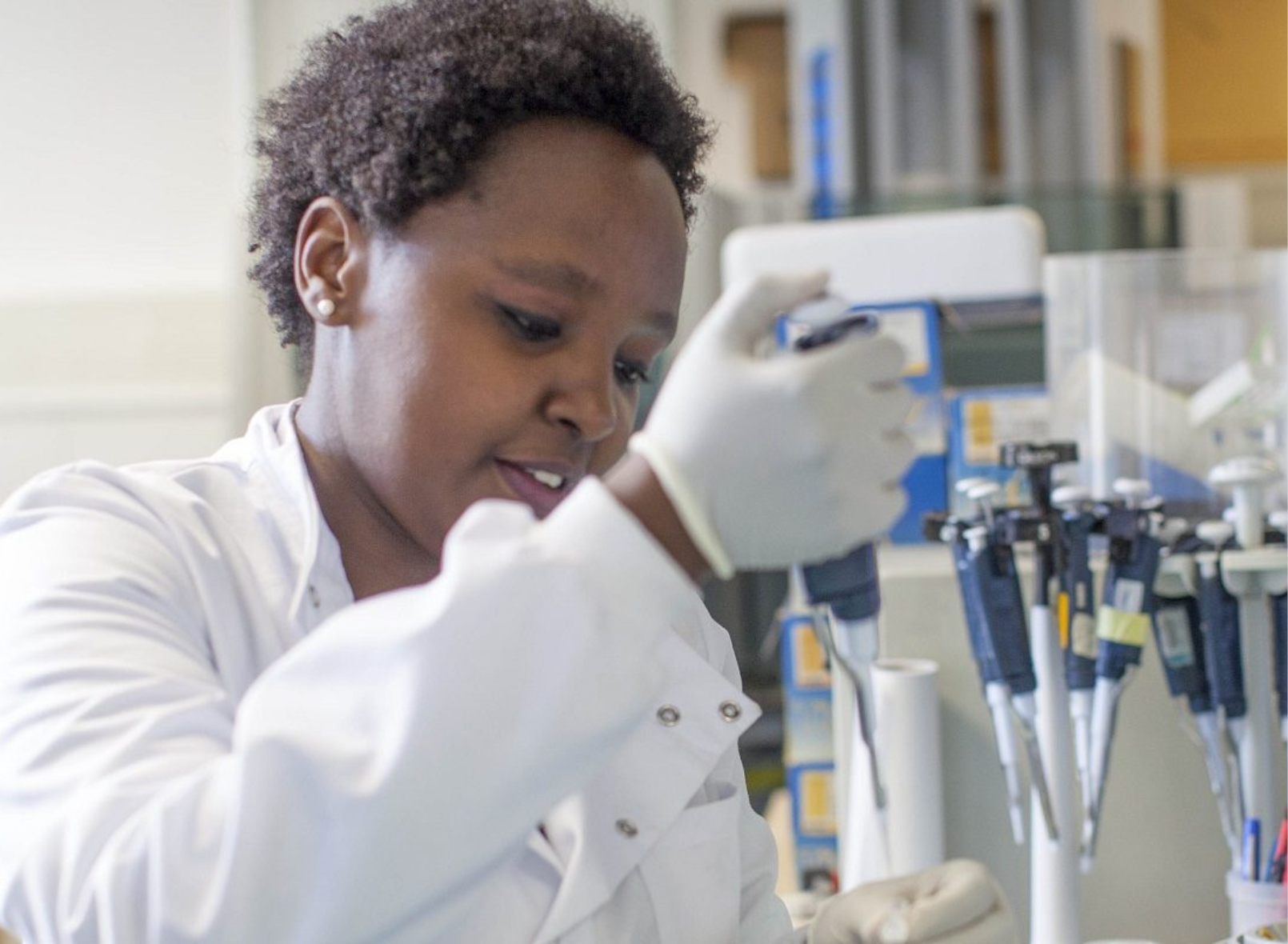 A researcher in a lab coat using a syringe in a medical lab