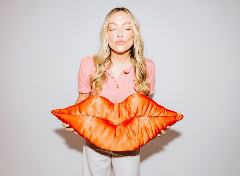 Picture of Cherry blowing a kiss and holding a large pair of kissing lips pillow prop
