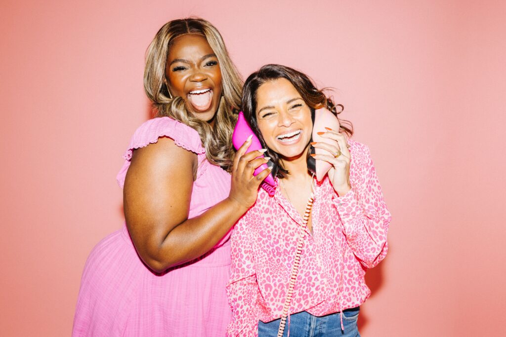 Dilly Carter and Tinuke Awe holding lip shaped phones up to their ears