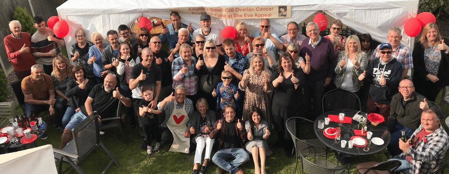 Photo of group of people with their thumbs up in front of banner that says 'Angela's small cell ovarian cancer research fund at the eve appeal'