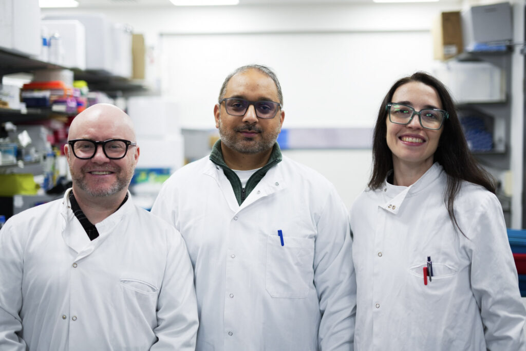 Photo of Mr. Hasan Mirza and his research team in a lab wearing lab coats.