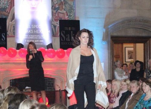 Photo of Saks fashion show runway, model walking down runway with audience watching. 