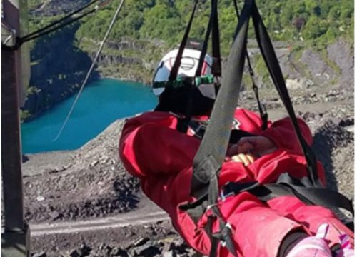 Photo of someone in zipline straps on edge of view and facing away from camera towards zipline
